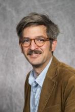 headshot of Jeremiah Heller; glasses, mustache, corduroy blazer 