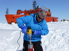 Ken Golden taking a sea ice core off the coast of East Antarctica, with the icebreaker Aurora Australis in the background. Photo taken by David Lubbers during the Sea Ice Physics and Ecosystem eXperiment II (SIPEXII), October 2012.